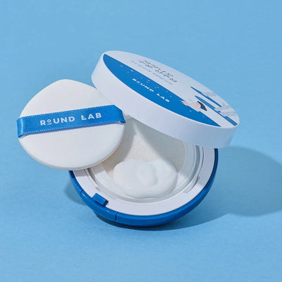 Round Lab Birch Juice Moisture Sun Cushion - Open Compact with Puff on Blue Background